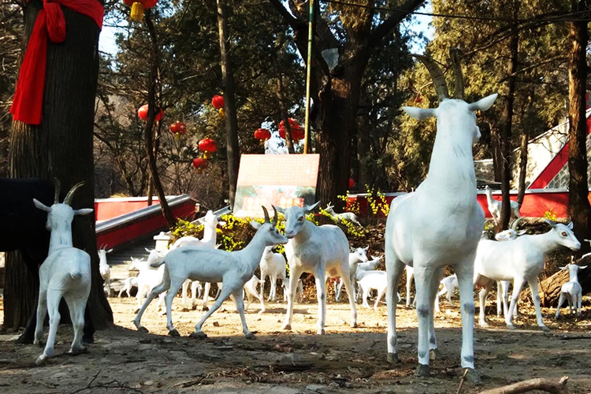 博仟北京雕塑公司创作的羊群着色水泥动物雕像正在吃草