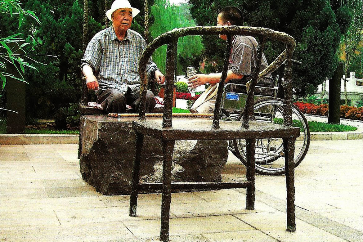 游人在博仟北京雕塑公司塑造的椅子雕塑创意设计小品下歇息